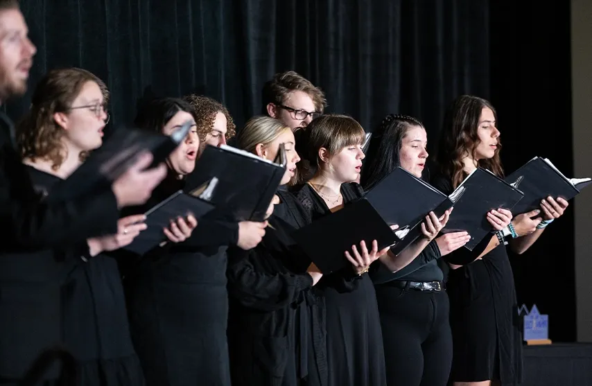 A group of choir members dressed in black singing together.